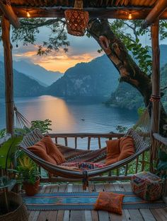 a hammock hanging from the side of a wooden deck next to a body of water