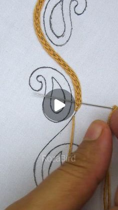 someone is stitching something on a piece of white fabric with a needle and thread