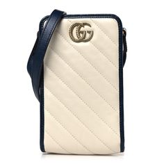 This is an authentic GUCCI Vintage Effect Calfskin Matelasse Diagonal Torchon GG Marmont Phone Crossbody Bag in Mystic White and Blue Agata. This stylish crossbody is crafted of white calfskin leather with blue leather trim. The bag features an adjustable blue leather shoulder strap, a textured aged gold Gucci GG logo and aged gold hardware. The top opens to a beige microfiber interior. Gucci Blue Shoulder Bag With Removable Pouch, Gucci Cream Rectangular Shoulder Bag, Blue Gucci Shoulder Bag, Blue Rectangular Gucci Bag, Gucci Cream Bag With Removable Pouch, Gucci Cream Crossbody Shoulder Bag, Blue Gucci Crossbody Shoulder Bag, Gucci White Bag With Removable Pouch, White Gucci Bag With Removable Pouch