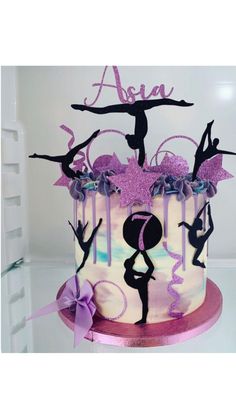 a cake decorated with acrobatic figures on top of a pink and purple plate