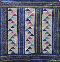 a blue quilt with colorful triangles on it