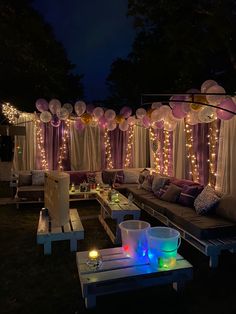 an outdoor seating area with lights and balloons on the walls, decorated for a party