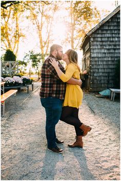 a man and woman kissing in front of a barn