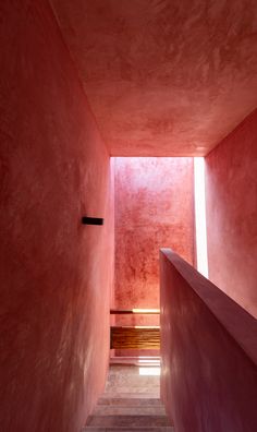 the stairs are made of concrete and have red walls with light coming in from them