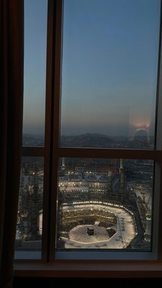 the view from an apartment window at dusk, looking down on a circular plaza and city lights