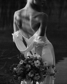 a black and white photo of a woman in a dress with flowers on her back