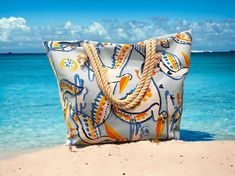 a blue and white bag sitting on top of a sandy beach next to the ocean