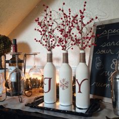 three white bottles with red berries in them sitting on a table next to other items