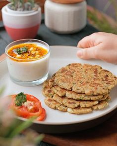 a white plate topped with food next to a bowl of soup and a glass of milk