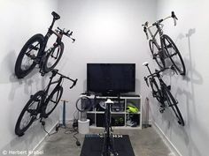 two bikes are hanging on the wall in front of a flat screen tv and other equipment