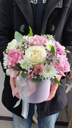 a person holding a pink and white flower bouquet in their left hand, with the man's black jacket over his shoulder