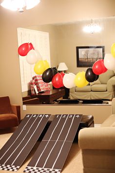 a living room filled with furniture and balloons in the shape of race track on top of carpet