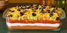 an enchilada dish with black olives, cheese and tomatoes in it