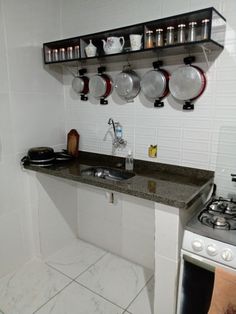 a kitchen with a stove, sink and shelves on the wall above it that hold pots and pans