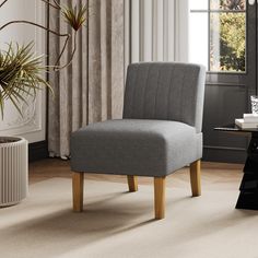 a gray chair sitting in front of a window next to a table with a potted plant