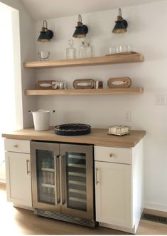 a kitchen with two shelves and an oven in the middle, one shelf has wine glasses on it