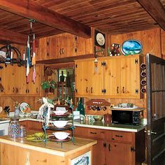 a kitchen with wood paneling and lots of clutter on the counter top area