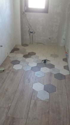 an unfinished bathroom with hexagonal tiles on the floor, and a window in the corner