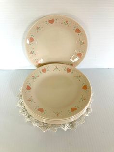 two white plates with hearts on them sitting on a doily next to each other