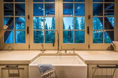 a kitchen with a sink and window overlooking the trees outside it is lit by lights