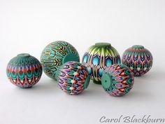 five colorful vases sitting next to each other on a white surface with a green button