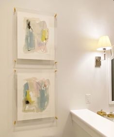 two paintings hanging on the wall in a bathroom