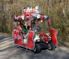 a car decorated with christmas decorations driving down the road in front of trees and bushes