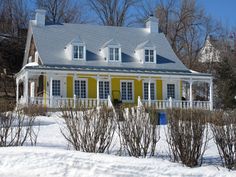 a yellow and white house in the middle of winter with snow on the ground around it