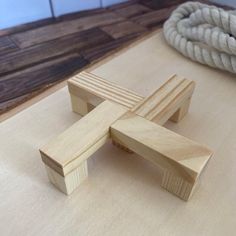 a wooden object sitting on top of a table next to a rope