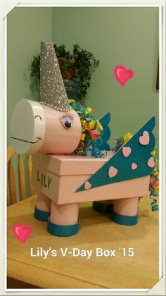 a wooden toy horse with a pink and blue hat on it's head sitting in a box