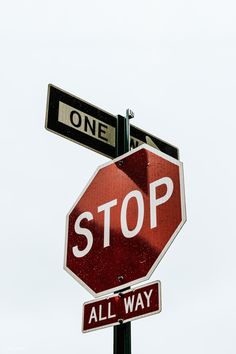 the stop sign has two street signs above it that read one way and all way