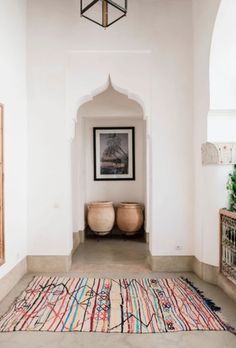 two vases sitting on top of a rug next to a doorway in a house