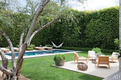 an outdoor patio with chairs and tables next to a swimming pool in the middle of a yard