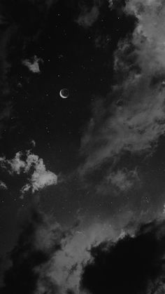 black and white photograph of the moon in the sky with clouds around it at night