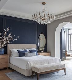 a bedroom with blue walls and white bedding, chandelier above the bed