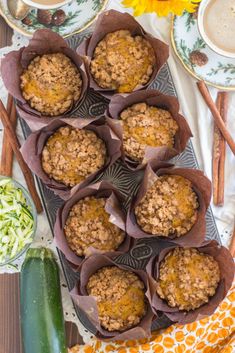 several muffins are sitting on a tray next to some vegetables and coffee cups