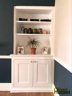 a white bookcase with two doors and a potted plant sitting on top of it