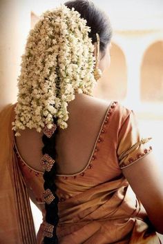 the back of a woman's head with flowers in her hair and braids