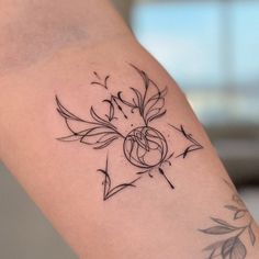 a woman's arm with a tattoo on it that has flowers and leaves in the center