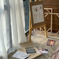 an easel and some pictures on the floor