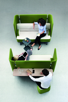 three people sitting on green couches in an office setting with white walls and flooring