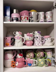 hello kitty coffee mugs are on shelves in a cupboard with other cups and saucers