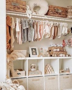 a closet filled with lots of baby clothes and baskets on top of white shelving