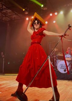 a woman in a red dress holding a pair of scissors on top of her head