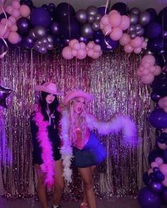 two women standing next to each other in front of balloons