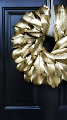 a gold wreath hanging on a black door