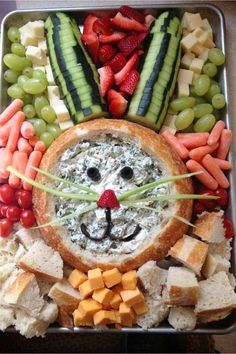 a metal tray filled with fruit and veggies next to a face made out of bread