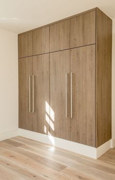 an empty room with wooden cabinets and hard wood flooring