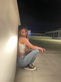 a woman sitting on the ground next to a wall