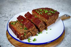 sliced meatloaf on a plate with green onions and seasoning next to it